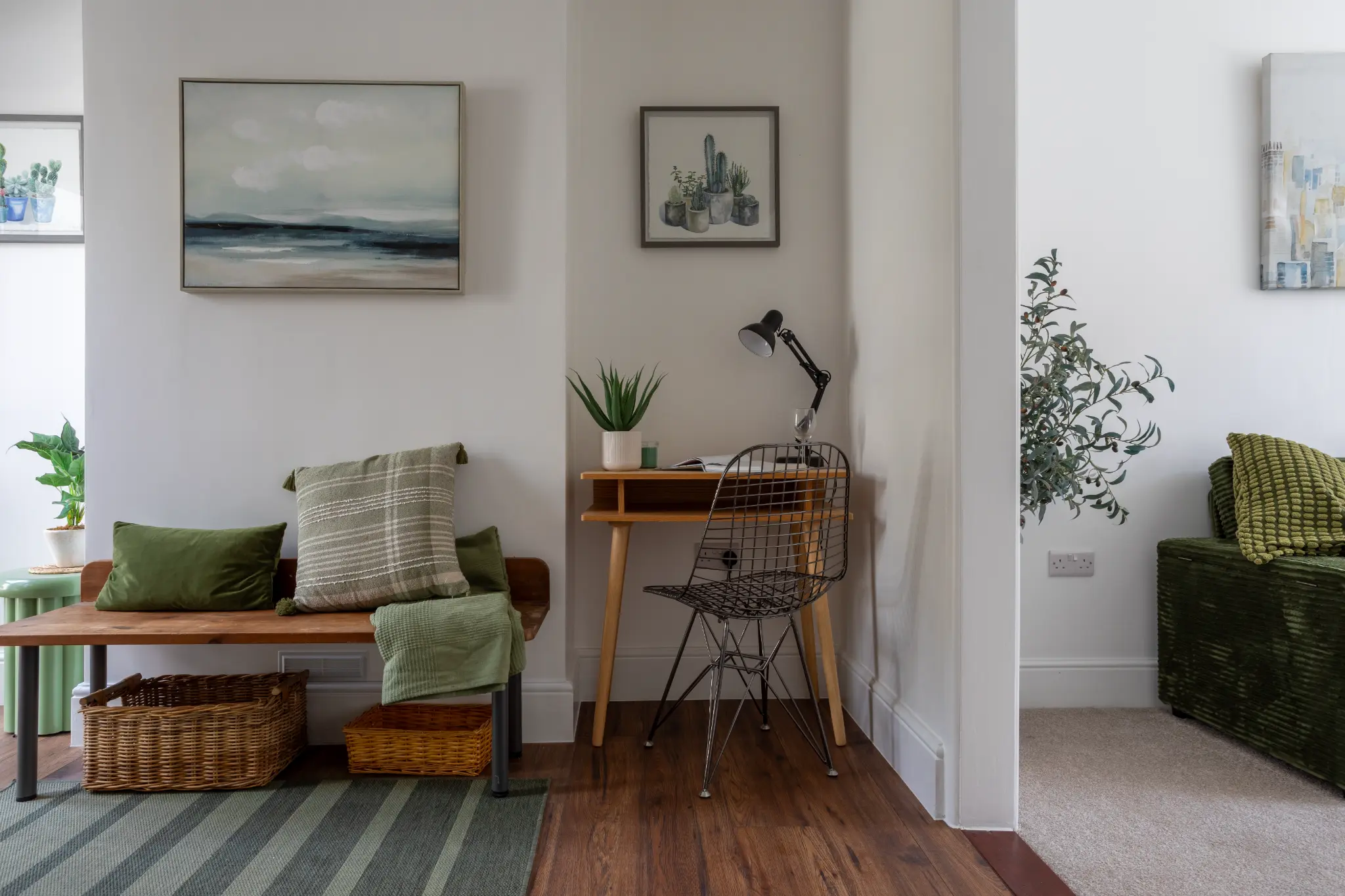 Hallway wider view with bench seating, desk area, landscape art and striped green rug