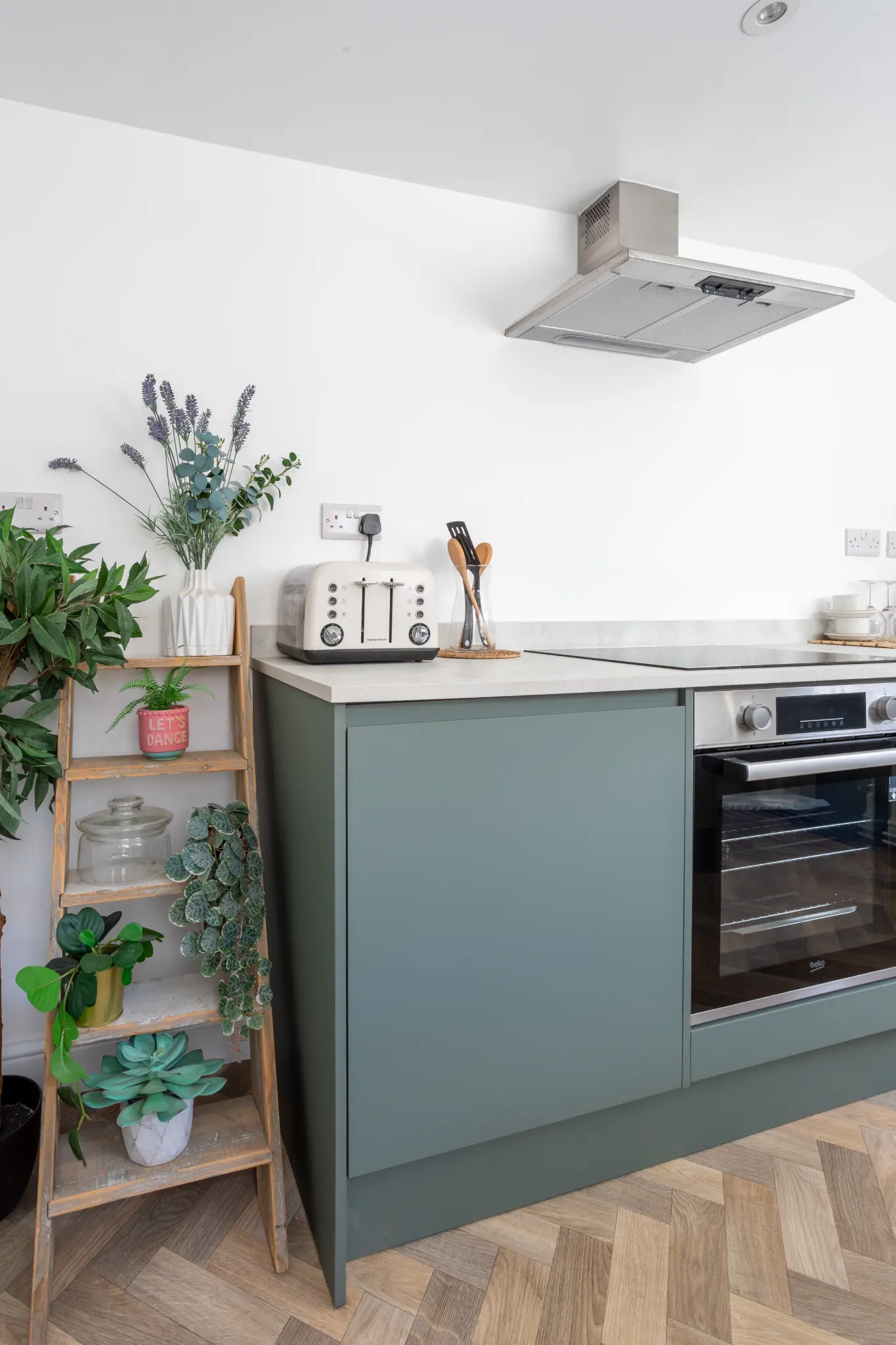 Detail of sage green kitchen island with built-in oven and herringbone floor in Bristol renovation