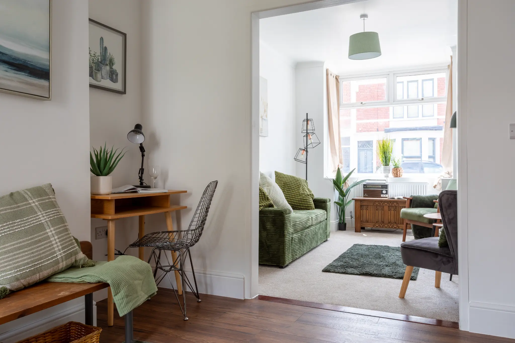 Hallway with wooden bench, compact desk nook with wire chair, and view through to green sofa in living room, Bristol renovation property photography