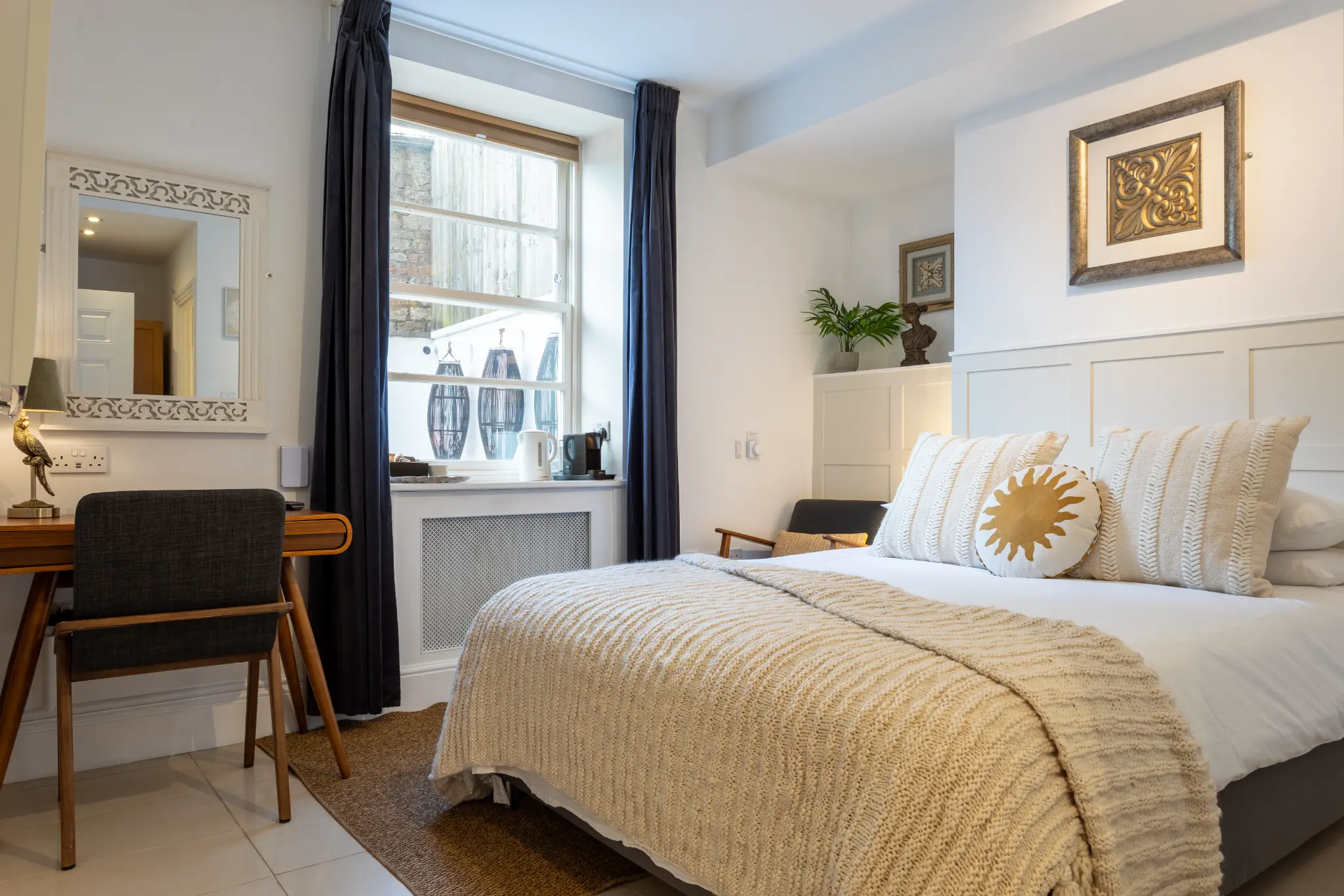 Cream and gold bedroom with knitted throw at Ferndale Mews Bristol