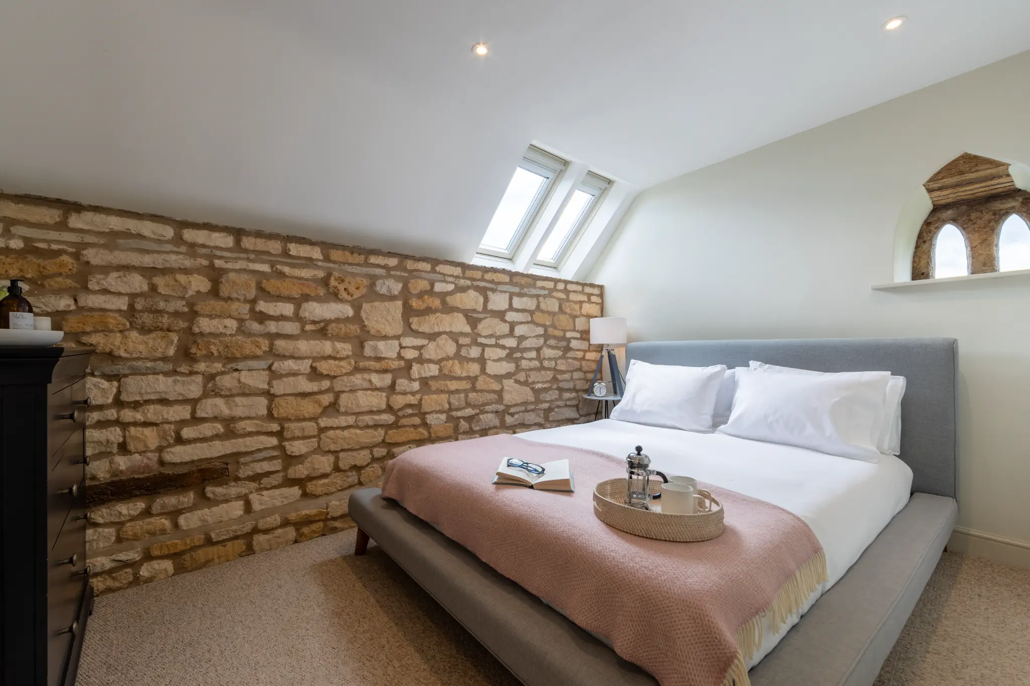 Bedroom with exposed stone wall and pink throw