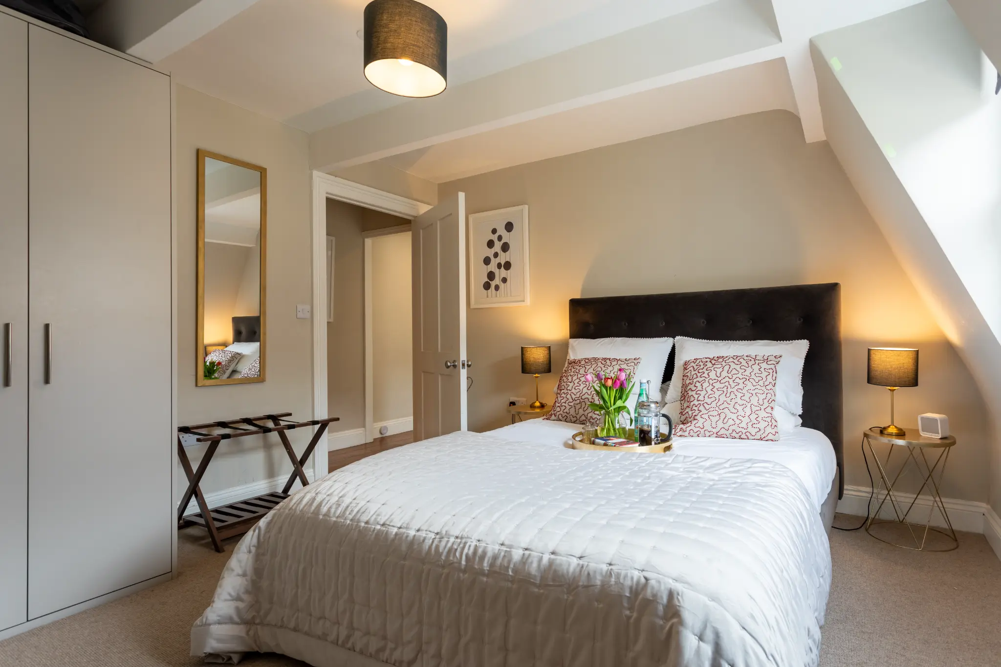 Bedroom with tulips and coffee tray on the bed at Milsom Apartments