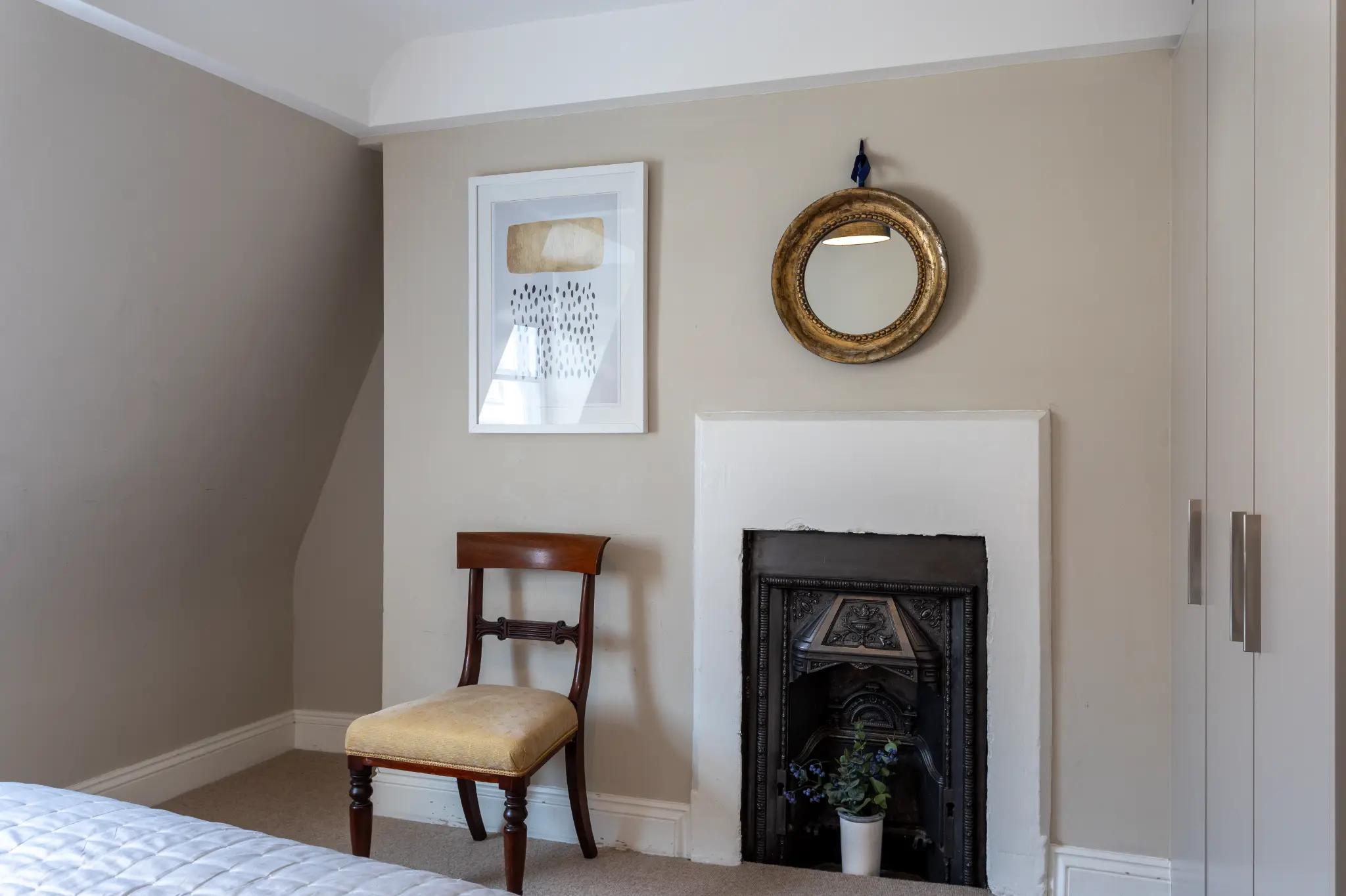 Victorian cast-iron fireplace with art print and antique mirror in bedroom