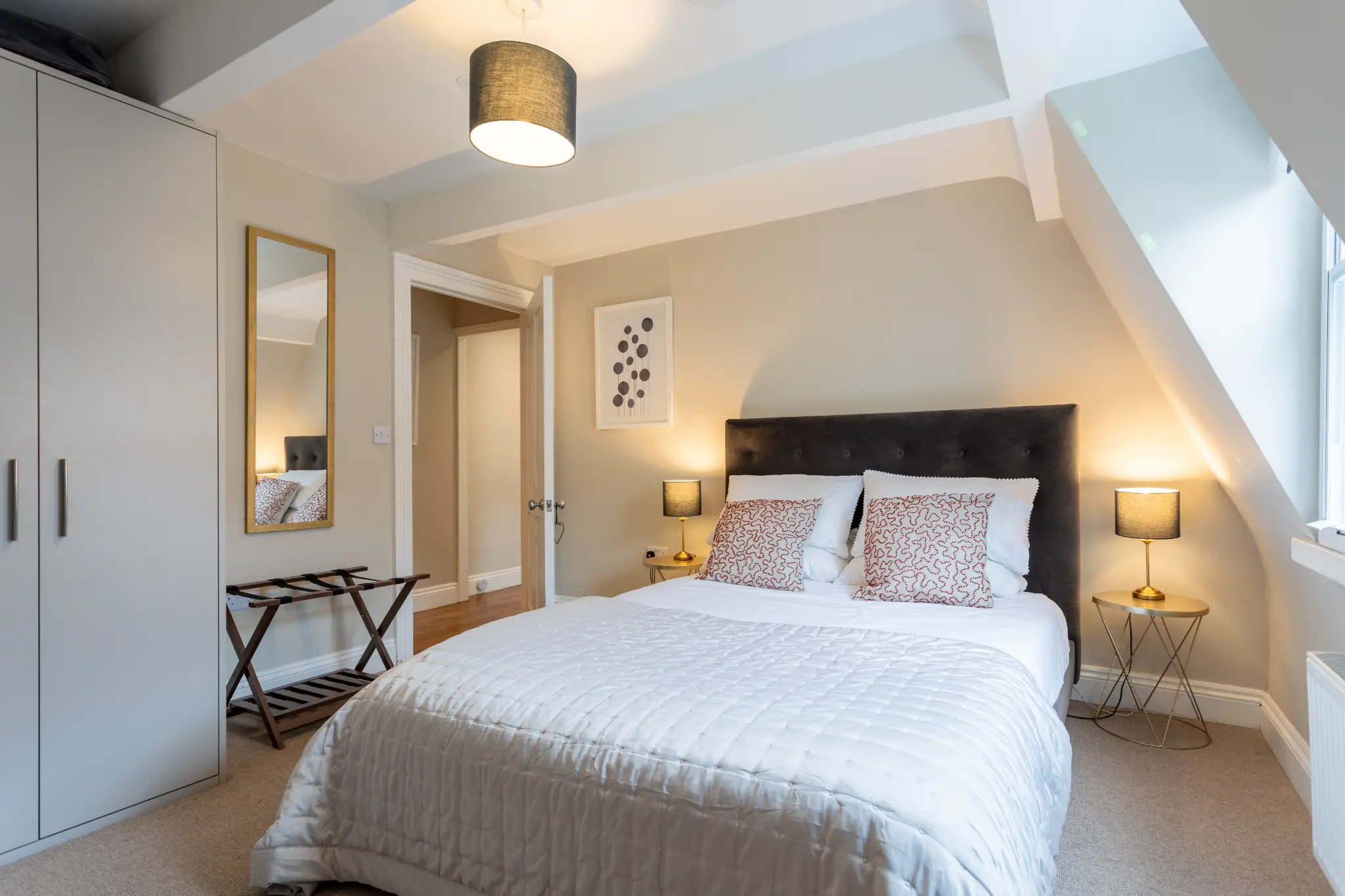 Main bedroom at Milsom Apartments Bath with upholstered headboard and warm lighting