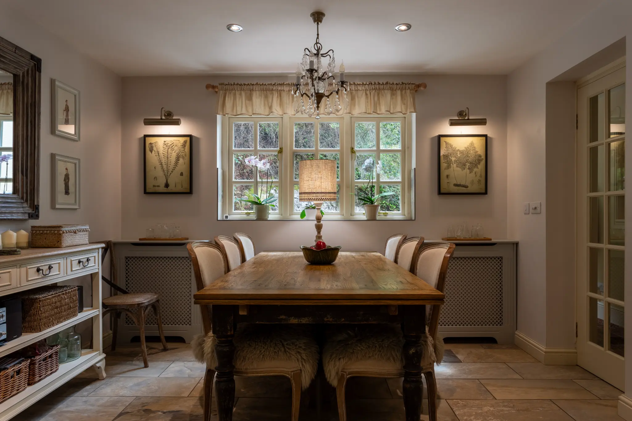 Cottage dining room lit by a chandelier and warm lamps