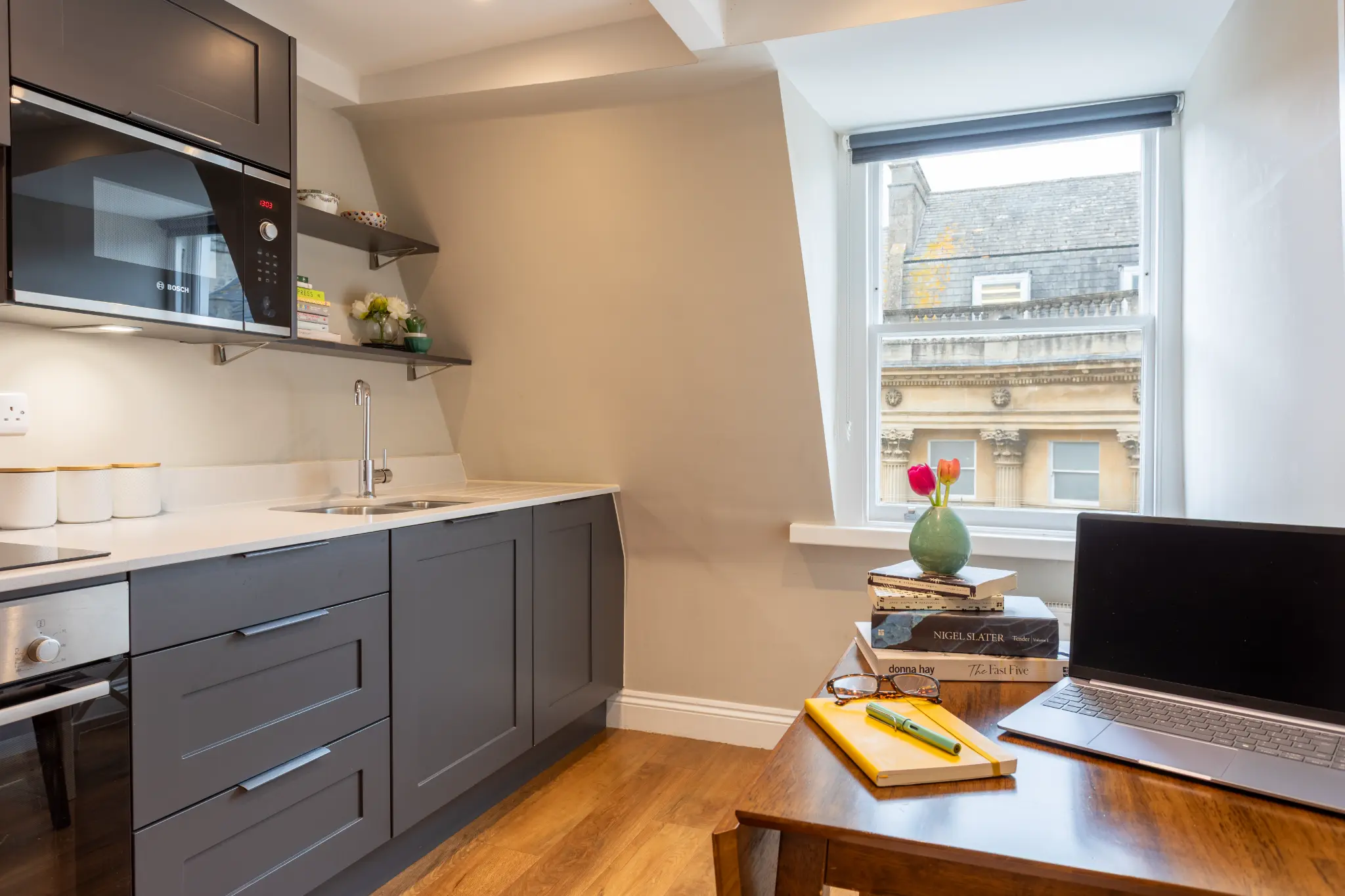 Kitchen workspace with laptop, cookbooks, and views over Bath