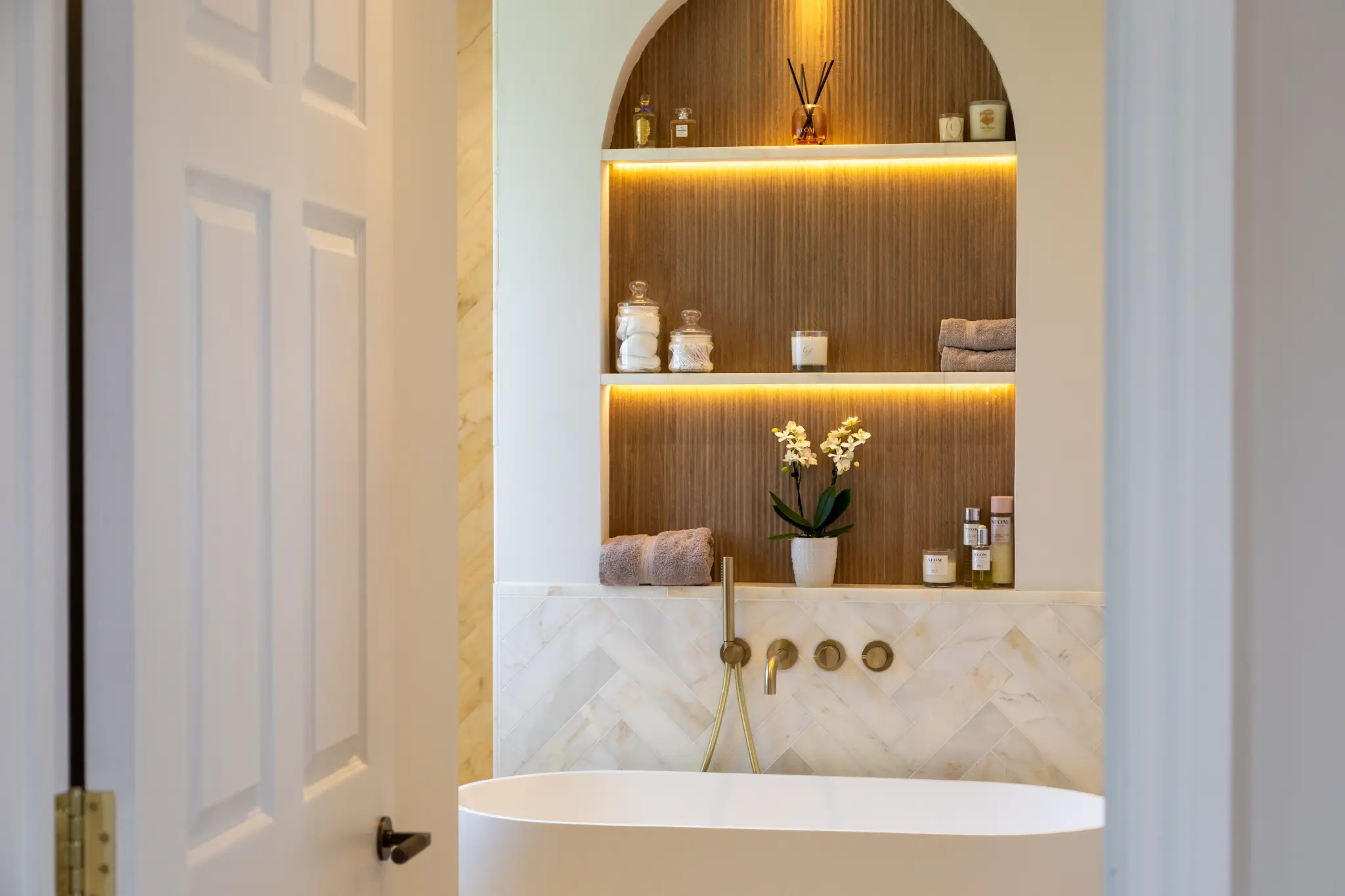 Arched lit alcove above a freestanding bath