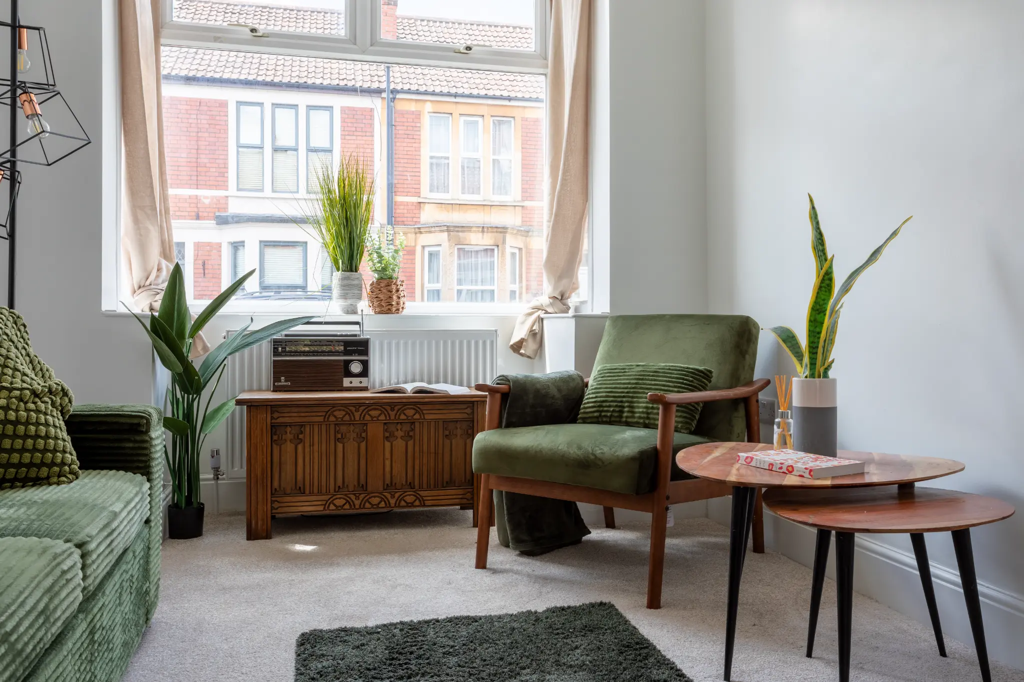 Living room alternate angle showing green armchair, wooden sideboard and bay window in Bristol terrace