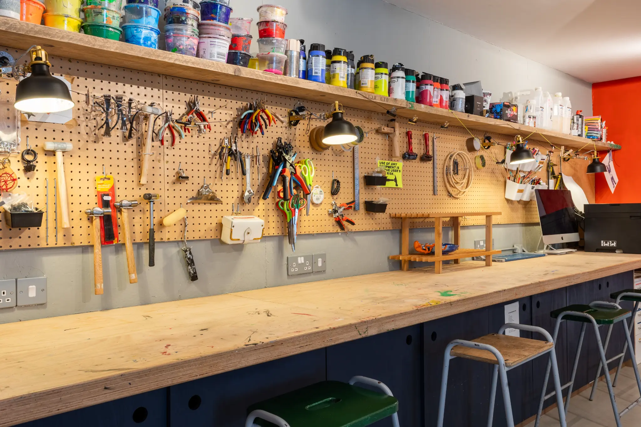 Detail shot of the workshop pegboard with hand tools, paint supplies, and task lighting