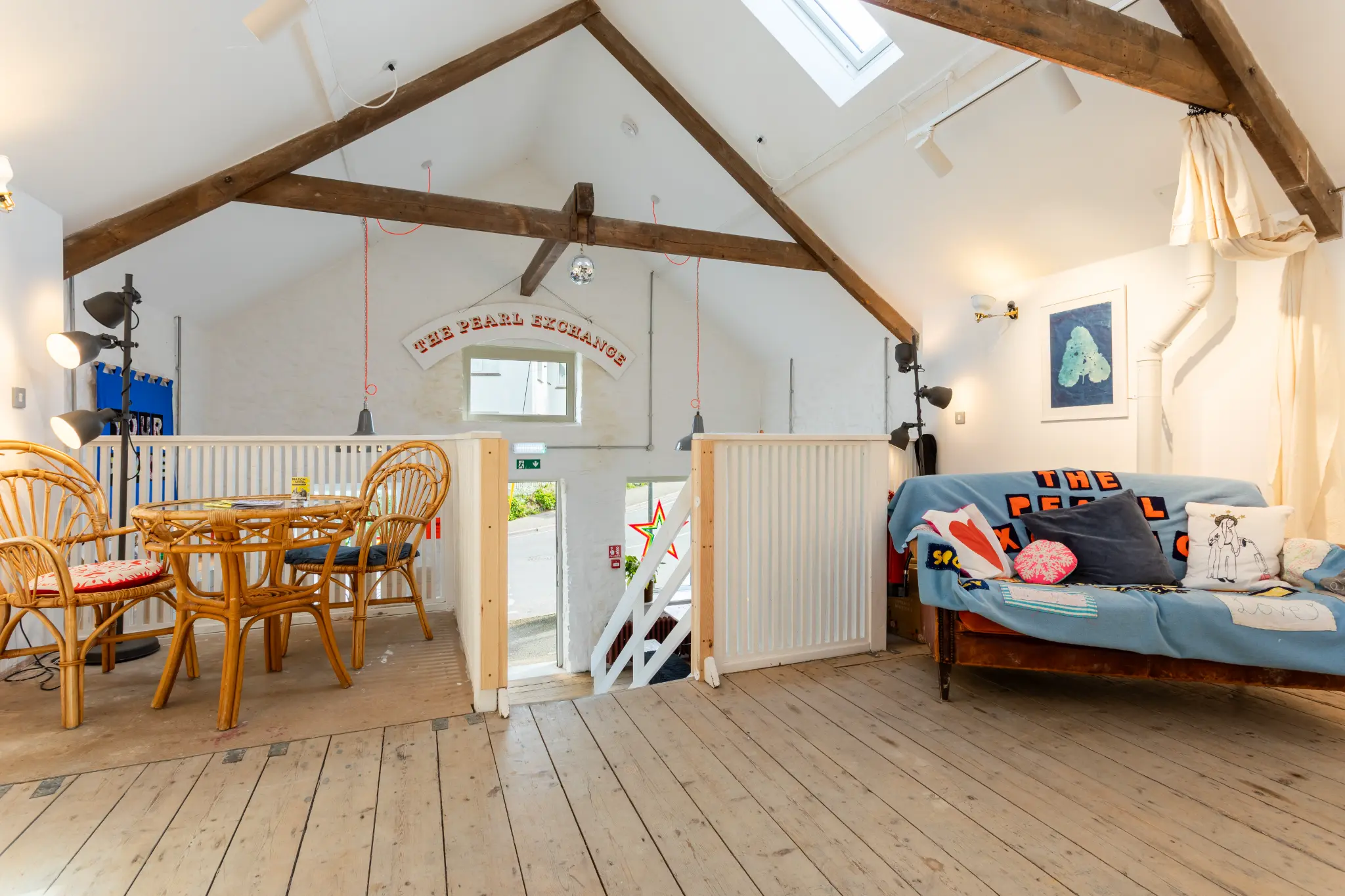 Mezzanine level with "The Pearl Exchange" sign, rattan chairs, sofa, and vaulted ceiling