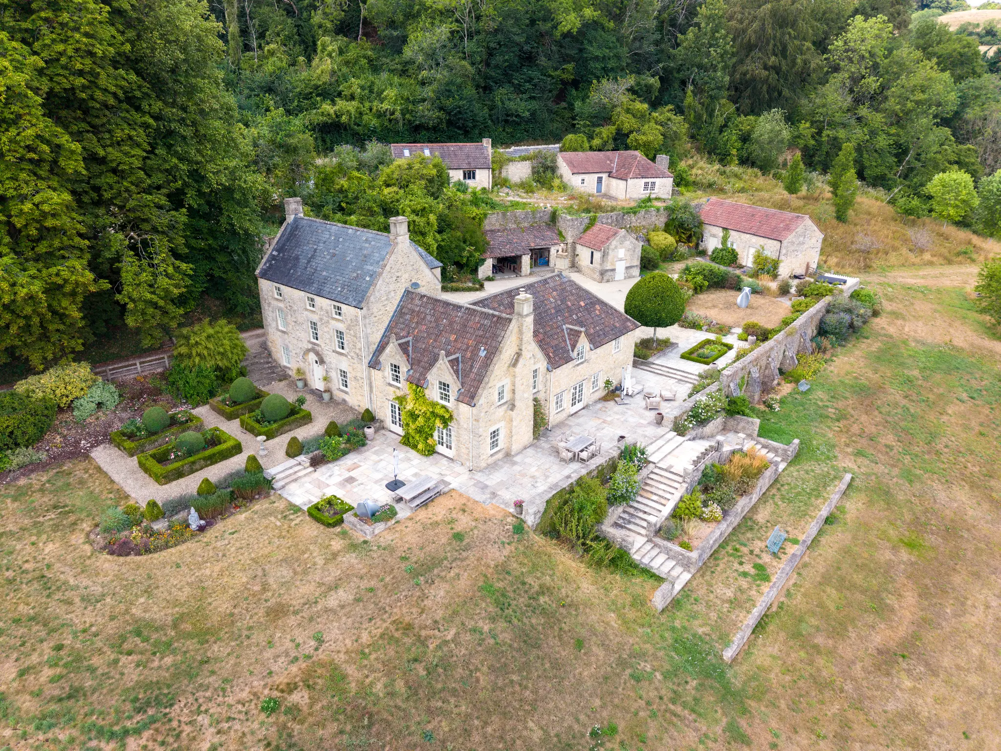 Aerial view of the historic Bath manor estate showing stone architecture, formal gardens, terraces, and surrounding countryside