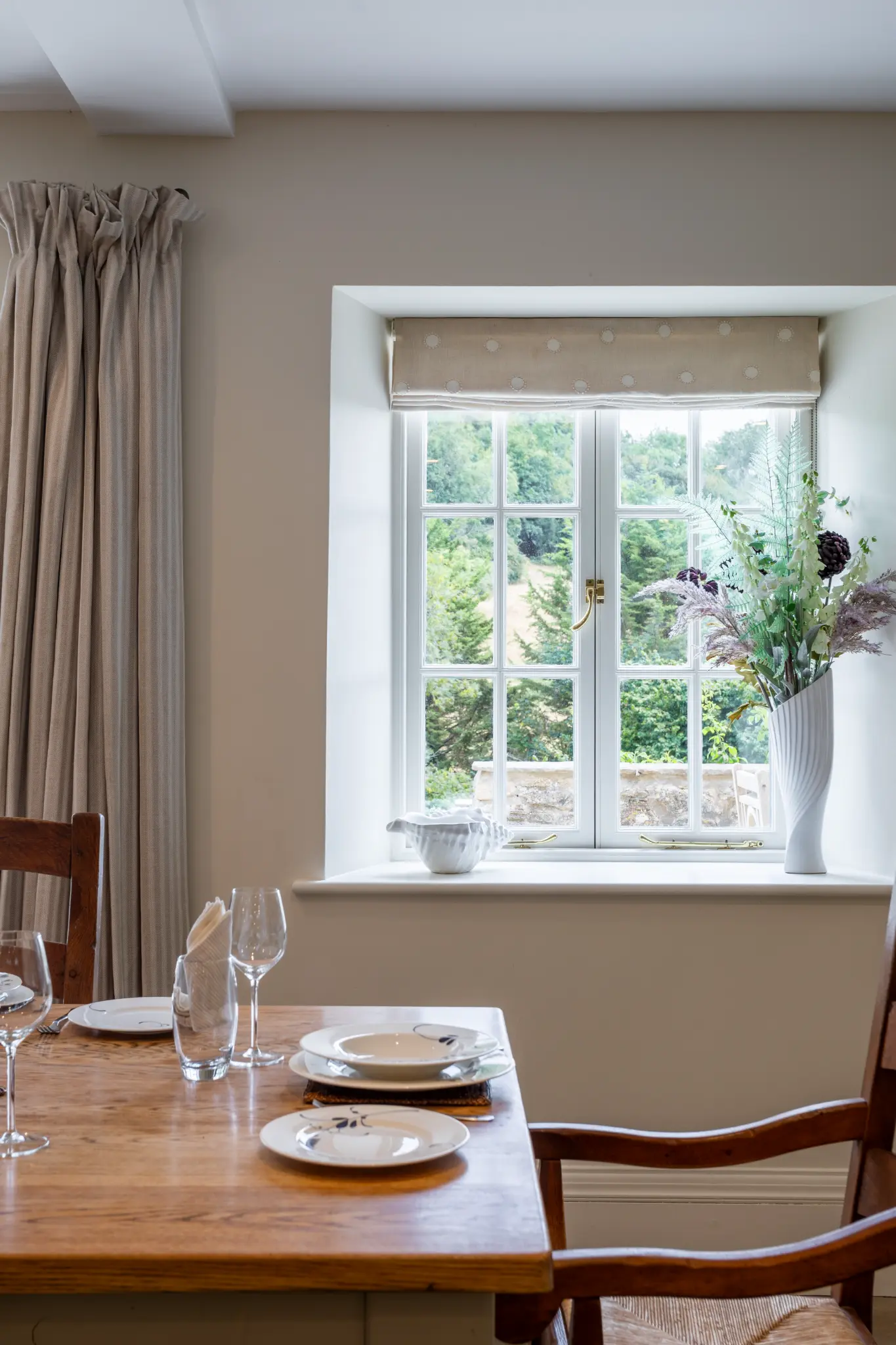 Rustic dining room in a luxury Bath manor featuring a set wooden table and scenic countryside window views