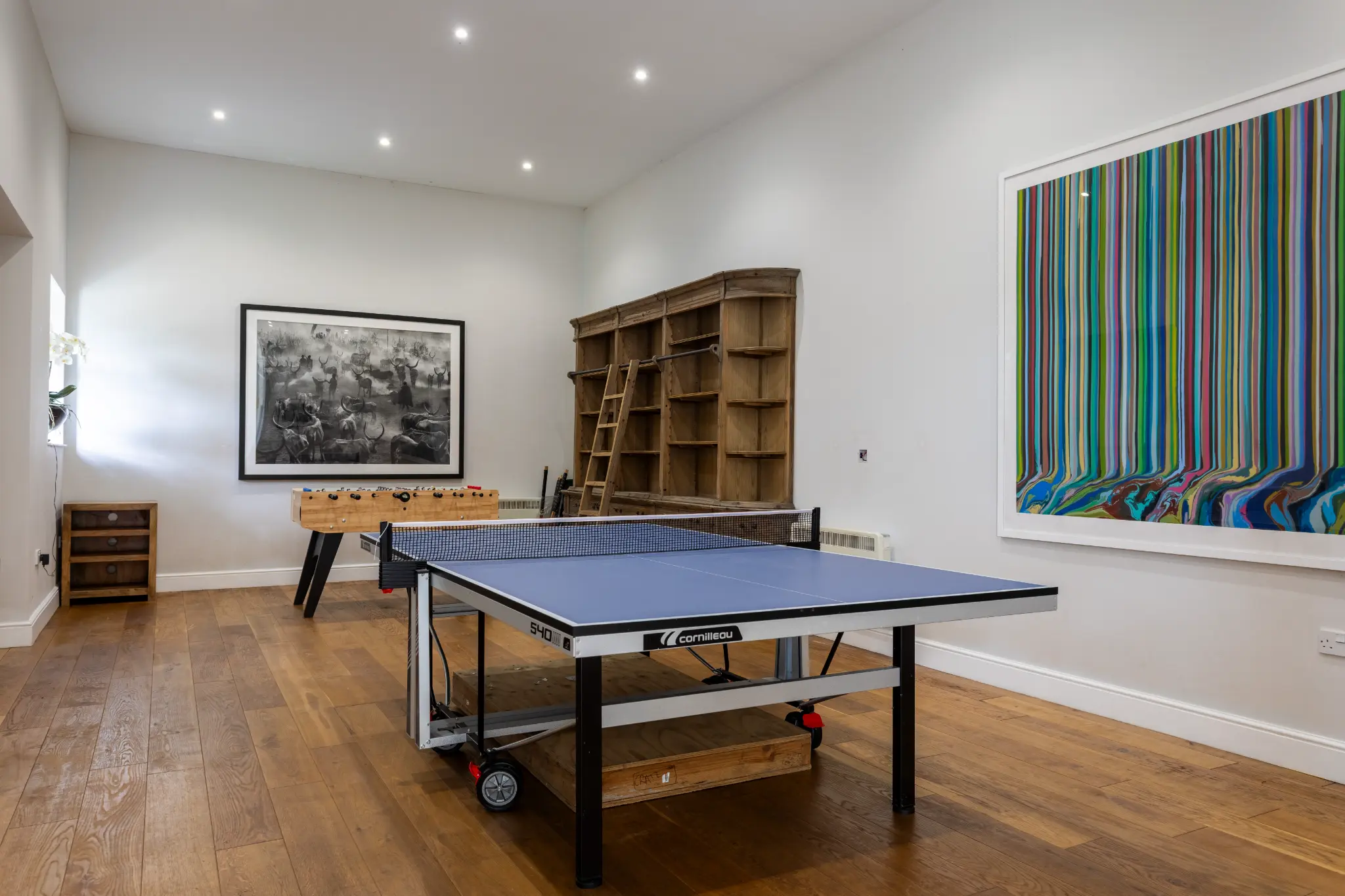 Spacious games room at a luxury Bath manor featuring a professional table tennis table, foosball table, and vibrant modern art