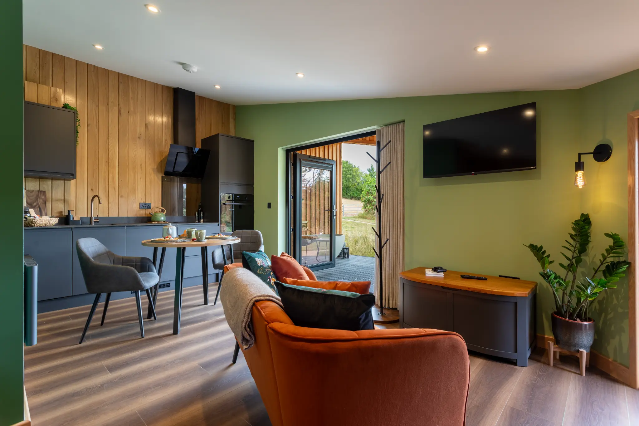 Open-plan interior of the Oak cabin at Ochre Hill with kitchen, lounge and doors open to the field