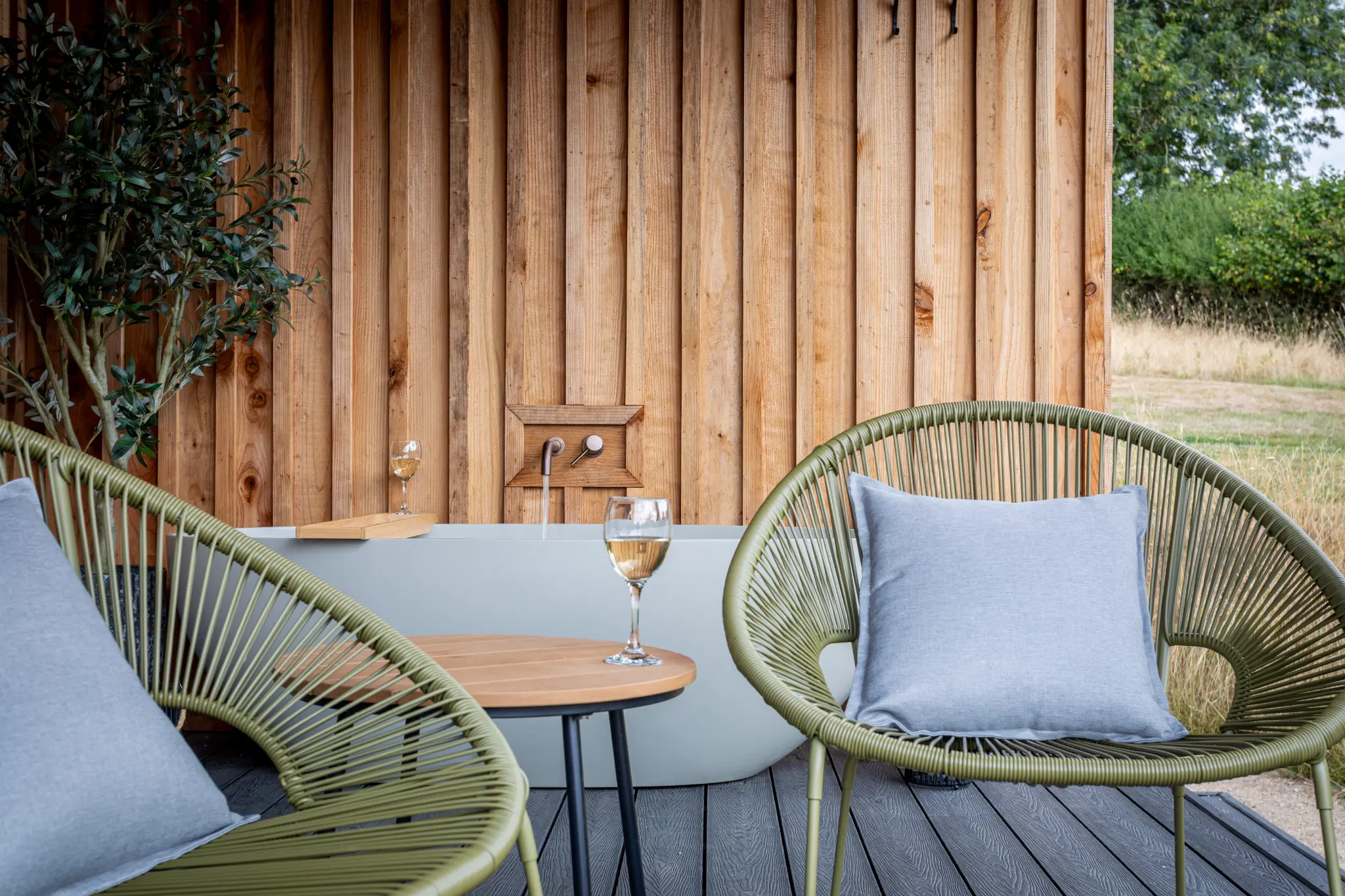 Styled deck seating detail with wine glass and cushions at a luxury lodge
