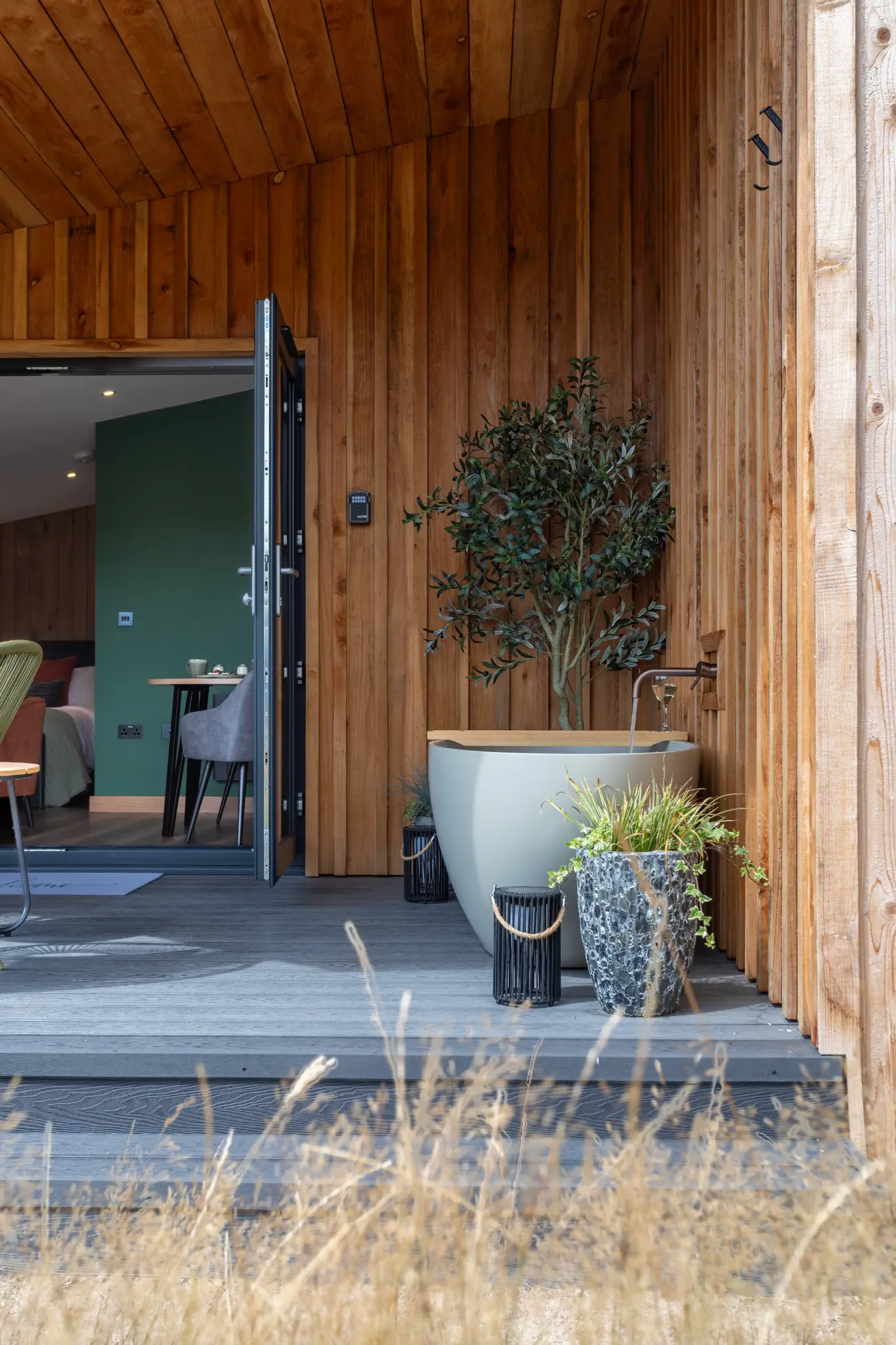 Covered deck at Ochre Hill with outdoor bath and dry meadow grass beyond
