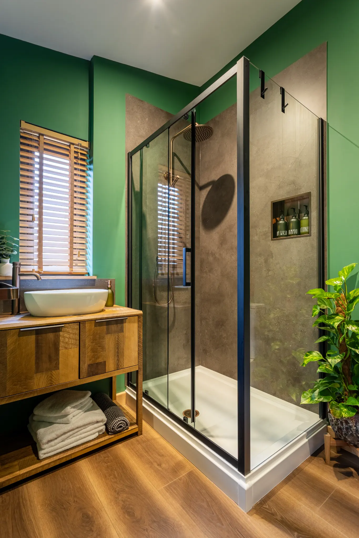 En-suite shower room with green walls, timber shutters and stone basin