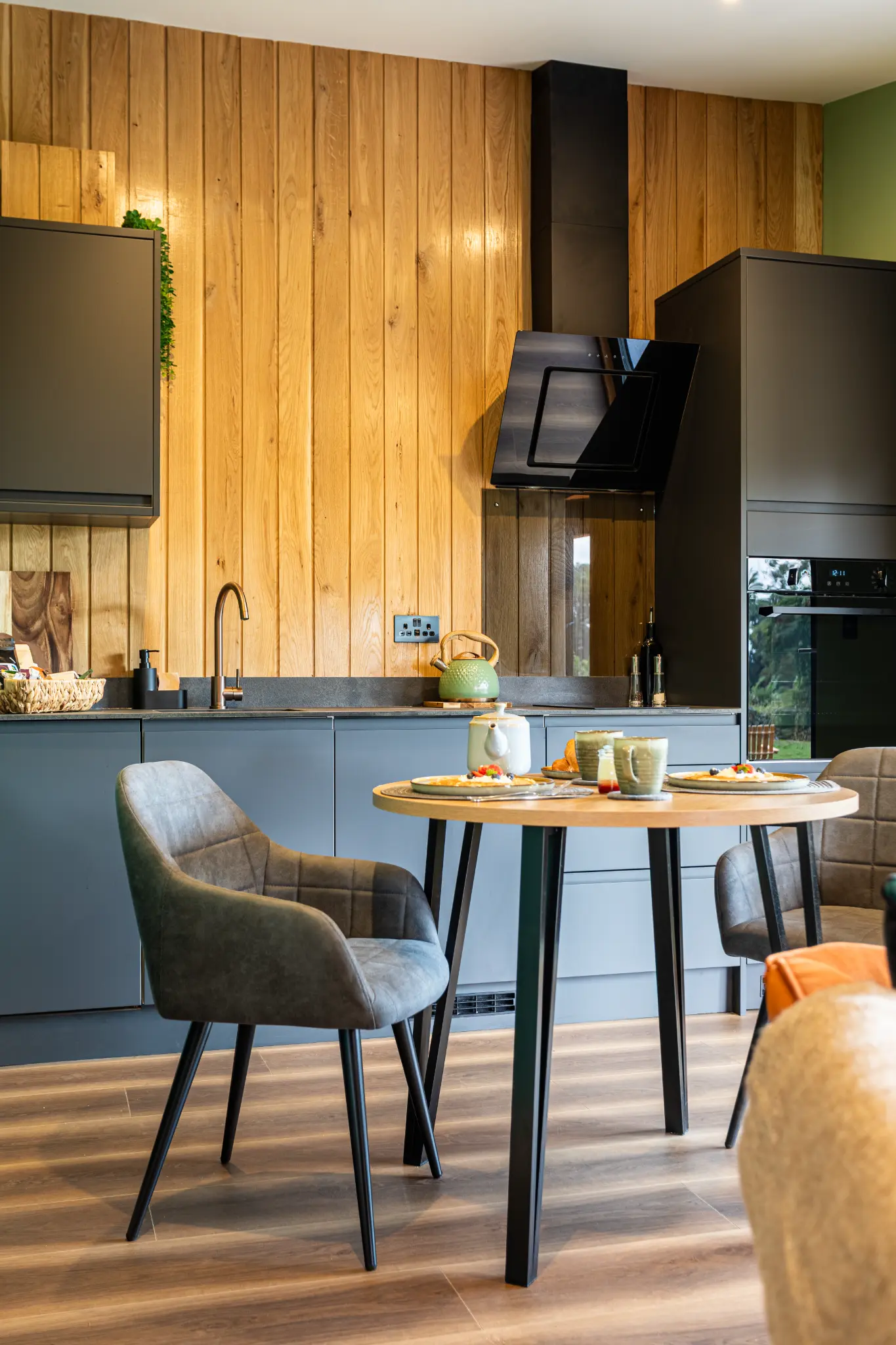 Compact fitted kitchen and bistro dining table with wood burner in a luxury lodge