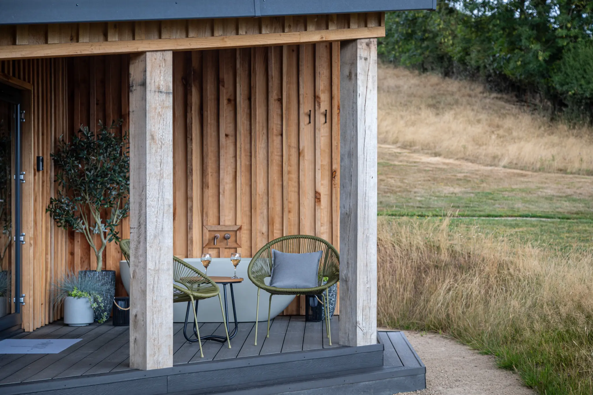 Covered deck with bistro table and chairs looking out over the meadow path