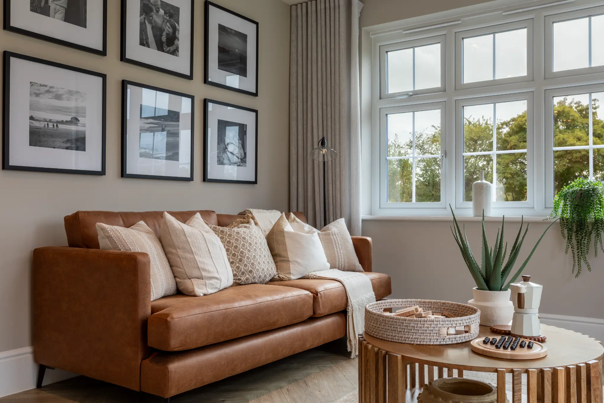 Redrow Homes show home lounge with a caramel sofa, layered neutral cushions and natural timber furniture