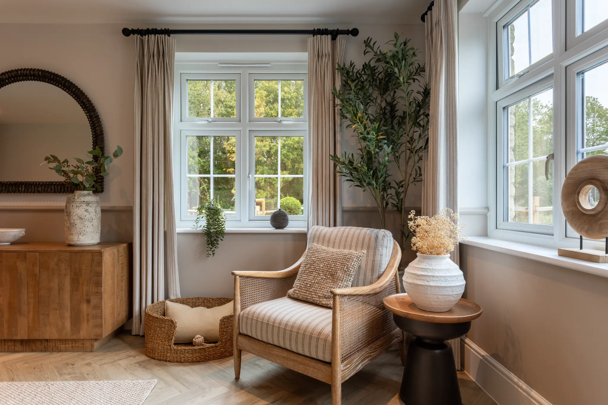 Wide Redrow Homes reading room with a cane armchair, warm timber cabinet and layered natural textures