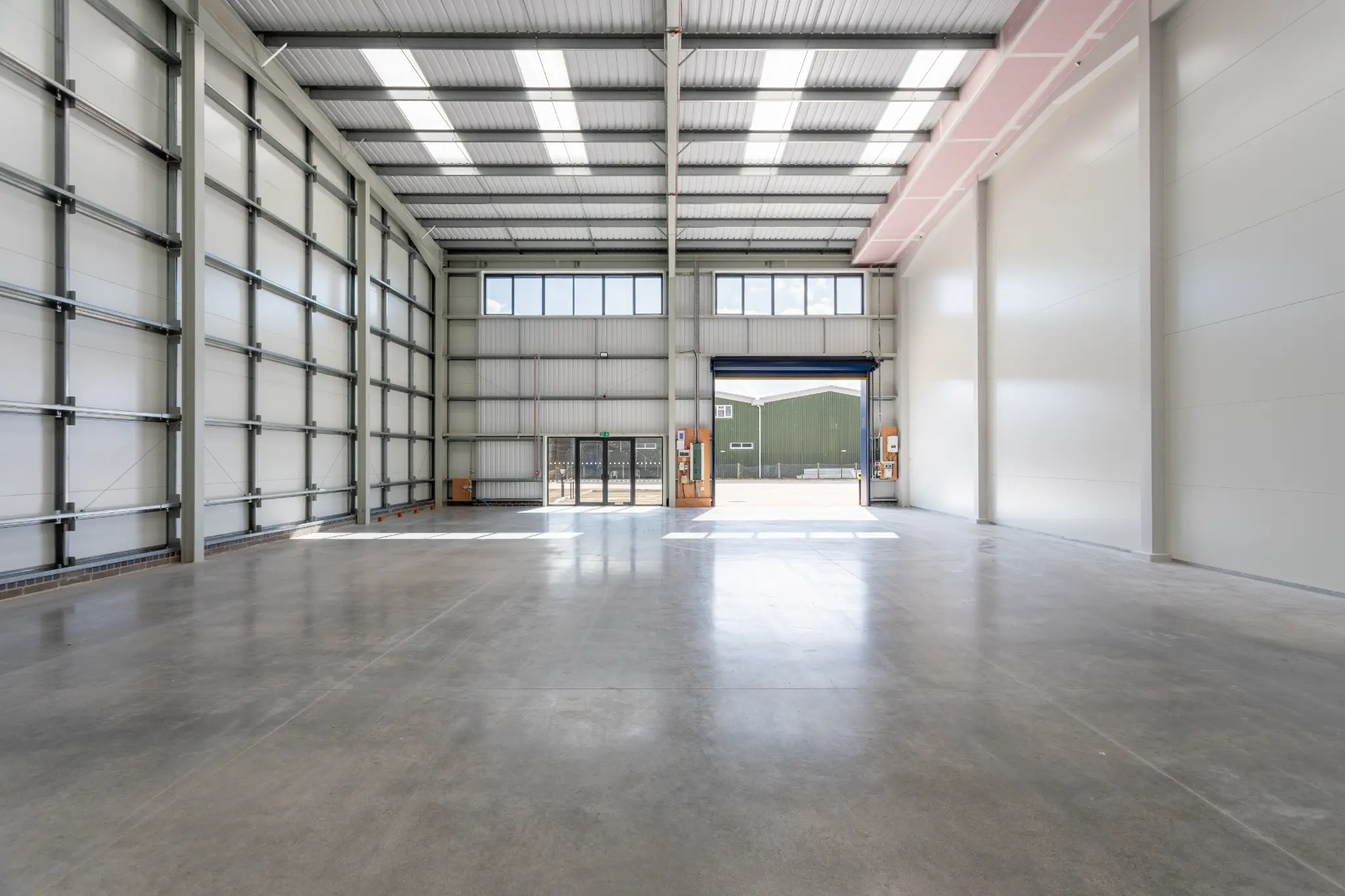 Warehouse interior with rooflights, steel frame and open roller shutter door