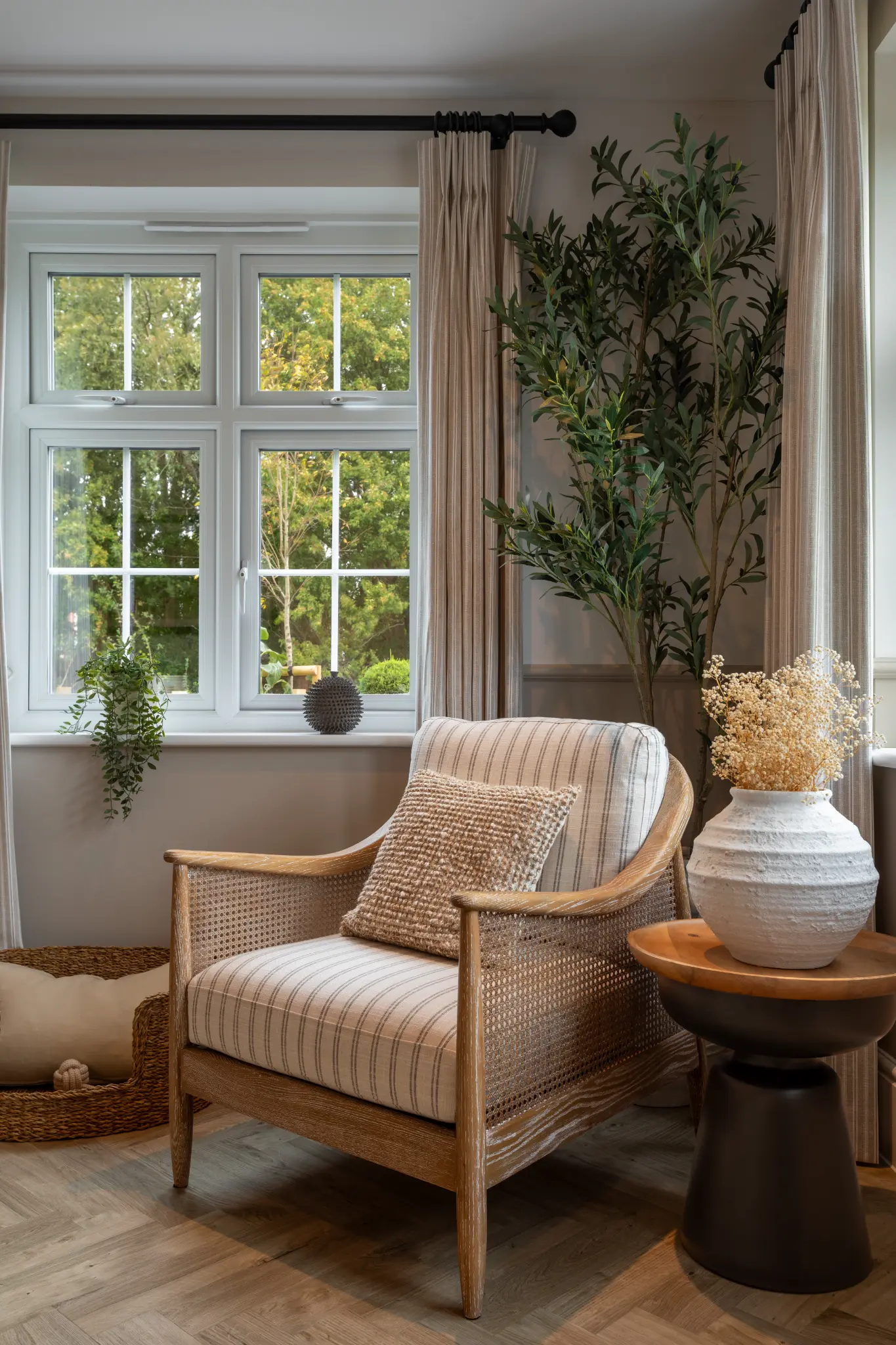 Cane armchair, textured cushion, dried flowers and greenery in a high-end show home reading corner