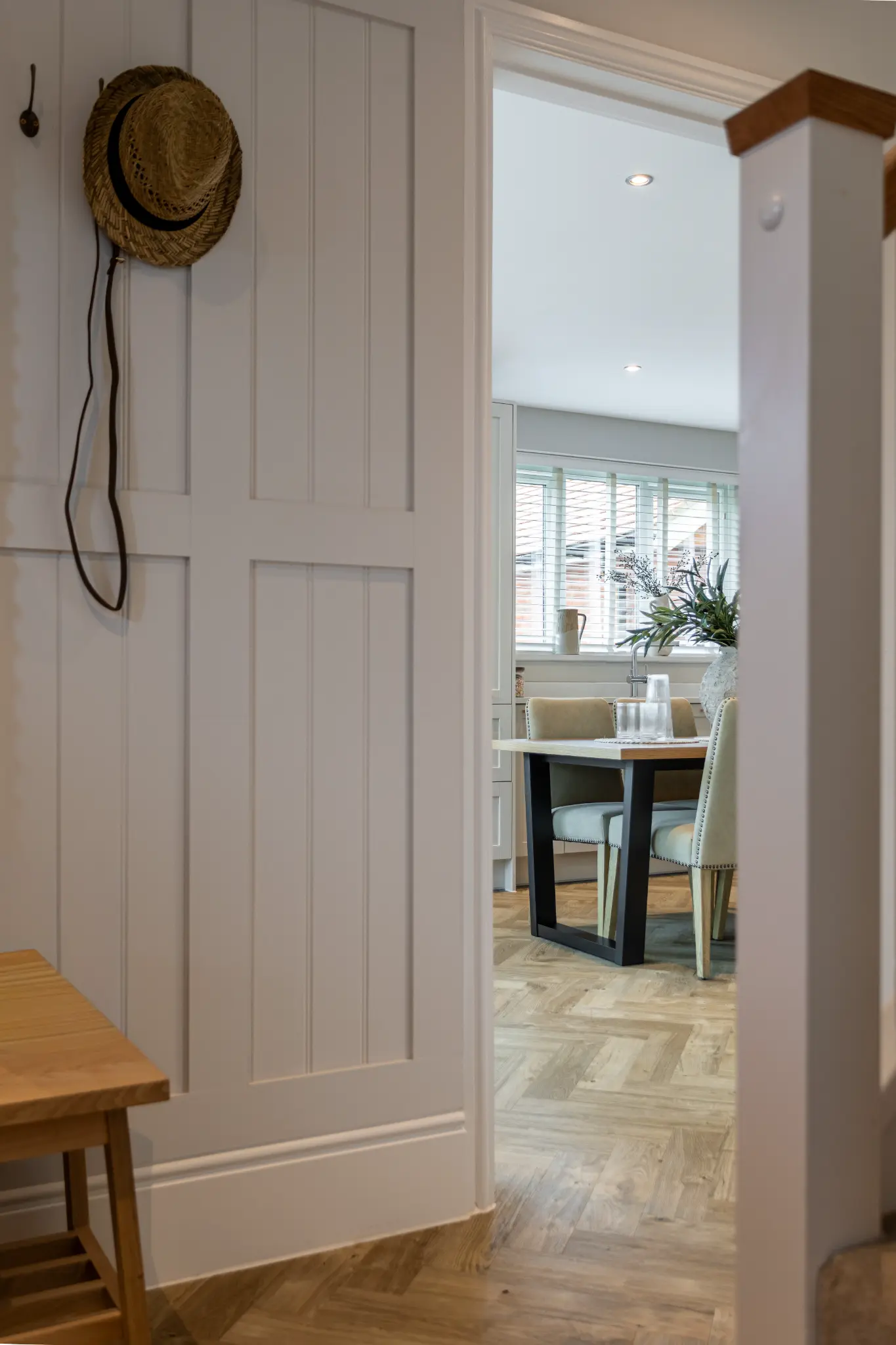 Panelled hallway and doorway leading into the kitchen and dining area of a high-end show home