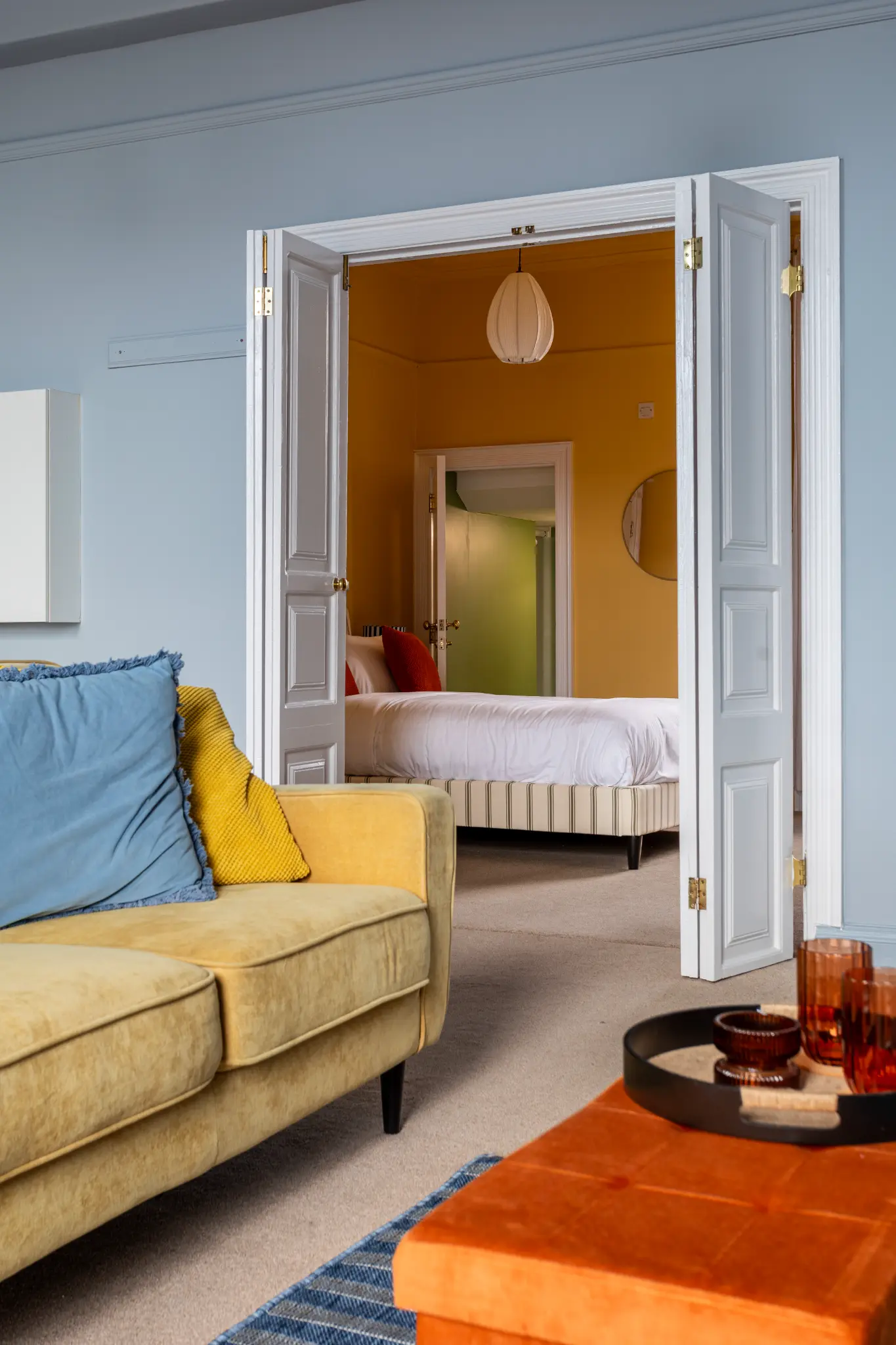 View from the blue living room through double doors into the amber bedroom of a Weymouth esplanade Airbnb